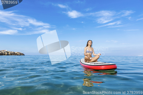 Image of Woman relaxing over a paddle surfboard