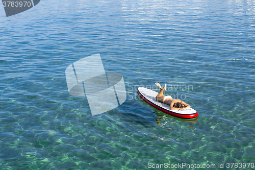 Image of Woman relaxing over a paddle surfboard