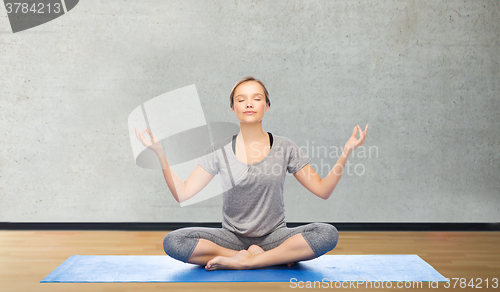 Image of woman making yoga meditation in lotus pose on mat