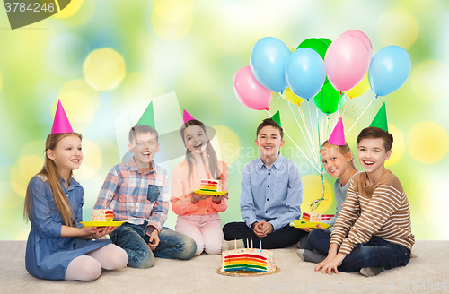 Image of happy children in party hats with birthday cake