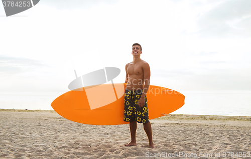 Image of smiling young man with surfboard on beach