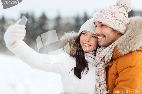 Image of happy couple taking selfie by smartphone in winter