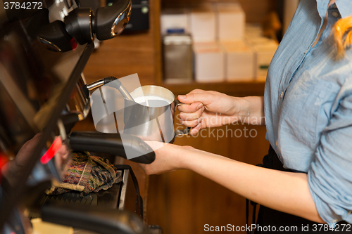 Image of close up of woman making coffee by machine at cafe