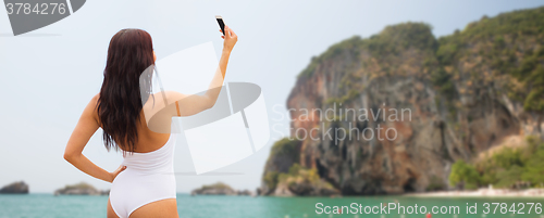 Image of young woman taking selfie with smartphone on beach