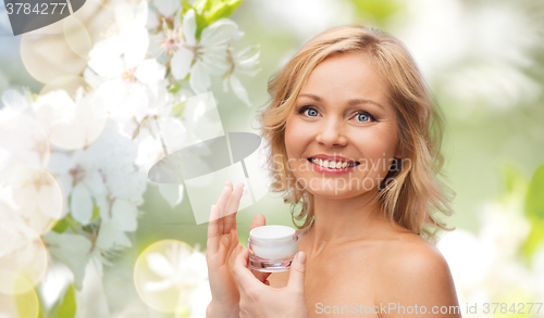 Image of happy woman applying cream to her face