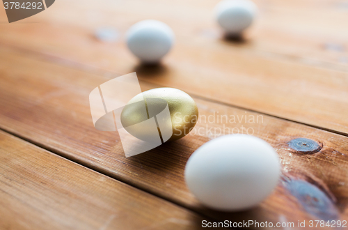 Image of close up of golden and white easter eggs on wood