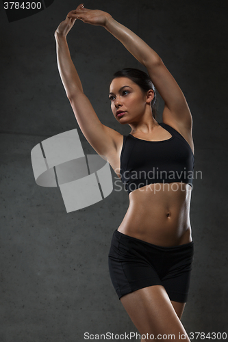 Image of young woman posing and showing muscles in gym