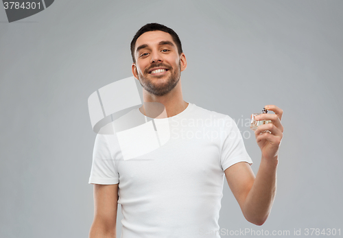 Image of smiling man with male perfume over gray background