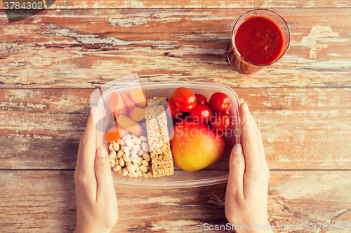 Image of close up of hands with vegetarian food in box