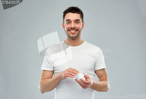 Image of happy young man with cream jar over gray