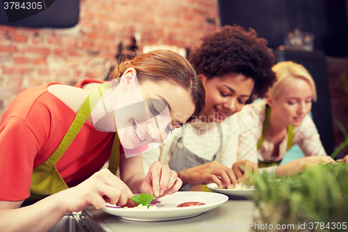 Image of happy women cooking and decorating dishes