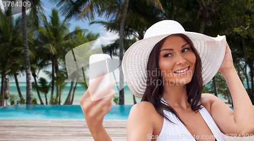 Image of young woman taking selfie with smartphone