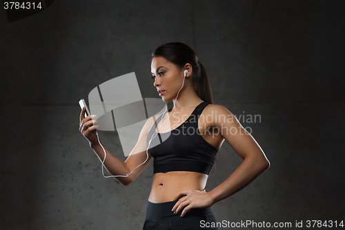 Image of woman with smartphone and earphones in gym