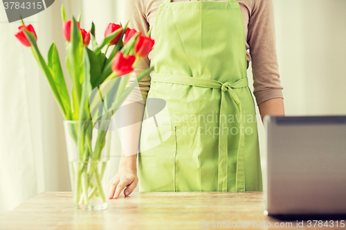 Image of close up of woman with tulips in vase and laptop