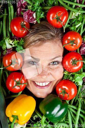 Image of Cute blond girl shot in studio with vegetables aroound the head