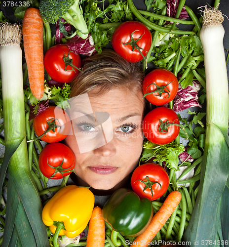 Image of Cute blond girl shot in studio with vegetables aroound the head
