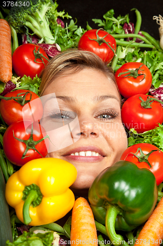 Image of Cute blond girl shot in studio with vegetables aroound the head