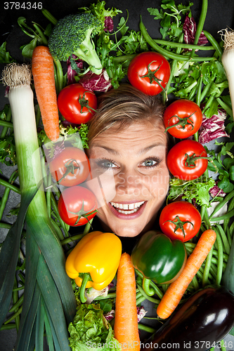 Image of Cute blond girl shot in studio with vegetables aroound the head