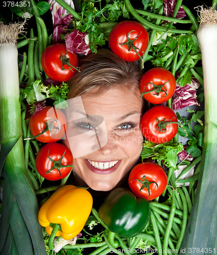 Image of Cute blond girl shot in studio with vegetables aroound the head