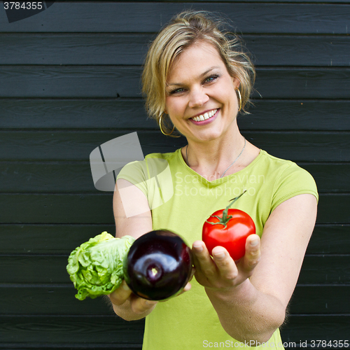 Image of Cute blond girl presenting vegetables