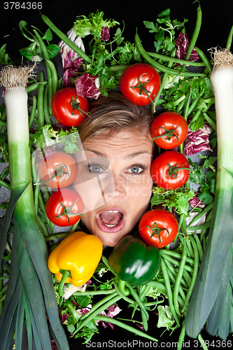Image of Cute blond girl shot in studio with vegetables aroound the head