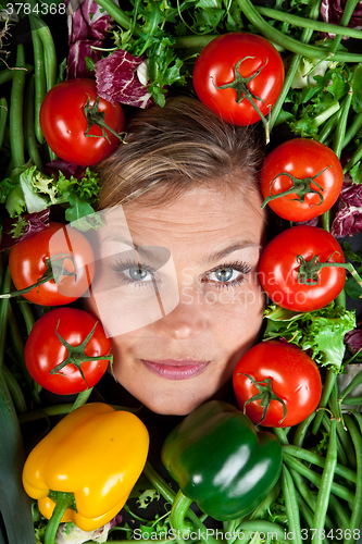 Image of Cute blond girl shot in studio with vegetables aroound the head