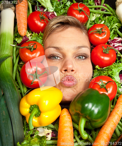 Image of Cute blond girl shot in studio with vegetables aroound the head