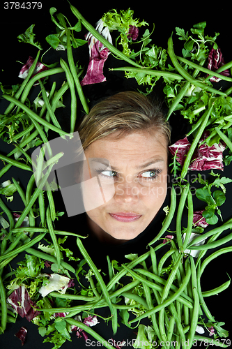 Image of Cute blond girl shot in studio with vegetables aroound the head