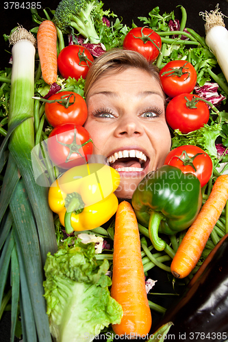 Image of Cute blond girl shot in studio with vegetables aroound the head