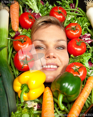 Image of Cute blond girl shot in studio with vegetables aroound the head