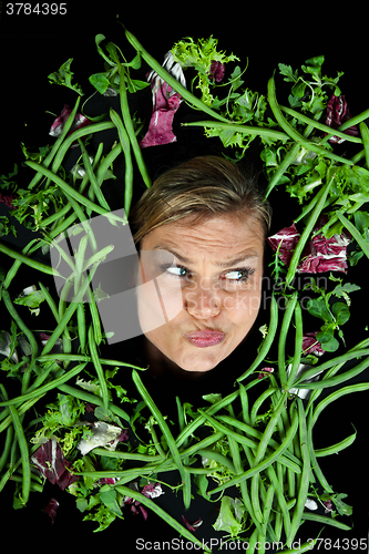 Image of Cute blond girl shot in studio with vegetables aroound the head