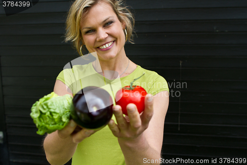 Image of Cute blond girl presenting vegetables