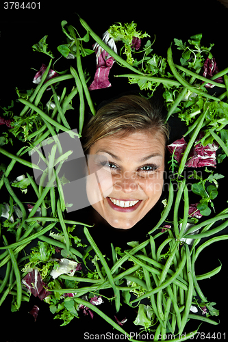 Image of Cute blond girl shot in studio with vegetables aroound the head