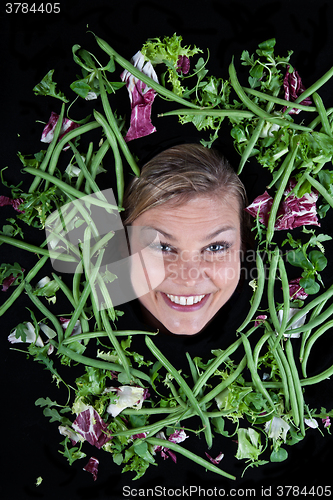 Image of Cute blond girl shot in studio with vegetables aroound the head