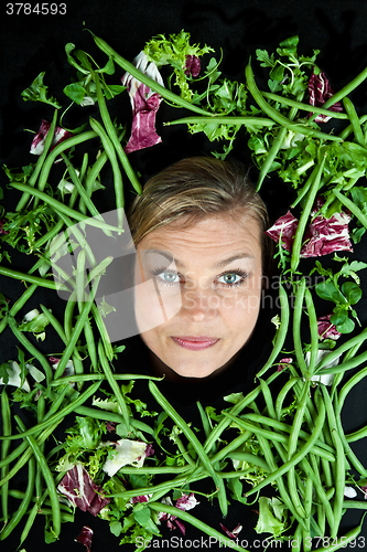 Image of Cute blond girl shot in studio with vegetables aroound the head