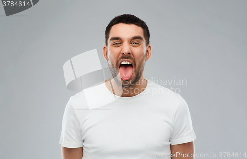 Image of man showing his tongue over gray background