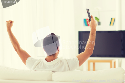 Image of man watching tv and supporting team at home