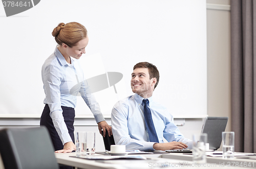 Image of businessman and secretary with laptop in office