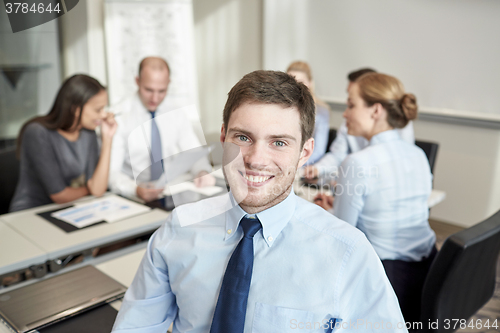 Image of group of smiling businesspeople meeting in office