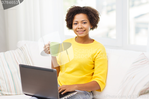 Image of happy african american woman with laptop at home