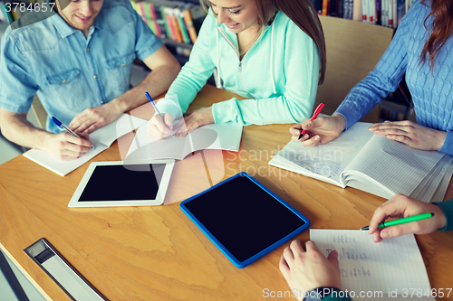 Image of happy students writing to notebooks in library