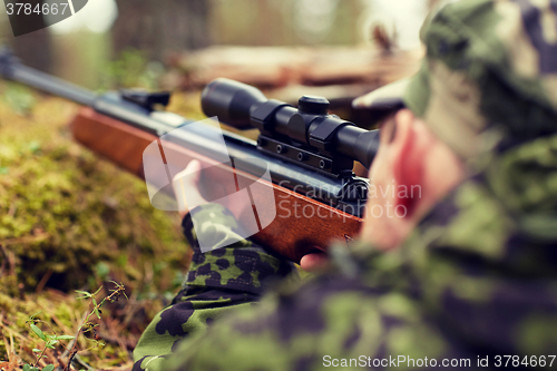 Image of soldier or hunter shooting with gun in forest