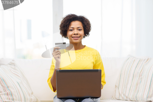 Image of happy african woman with laptop and credit card