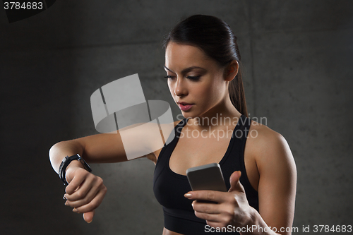 Image of woman with heart-rate watch and smartphone in gym