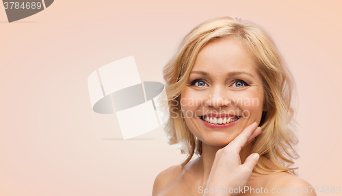 Image of smiling woman with bare shoulders touching face