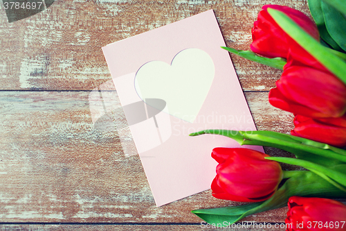 Image of close up of tulips and greeting card with heart