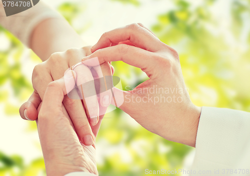 Image of close up of lesbian couple hands with wedding ring