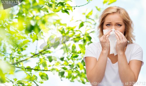 Image of unhappy woman with paper napkin blowing nose