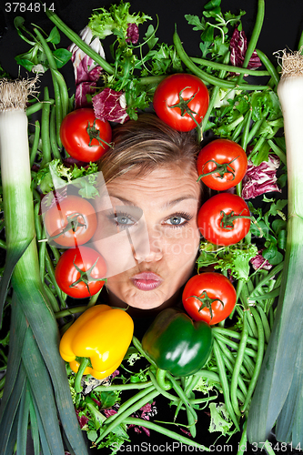 Image of Cute blond girl shot in studio with vegetables aroound the head