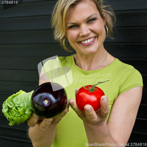 Image of Cute blond girl presenting vegetables